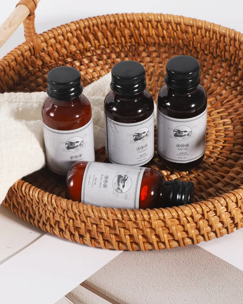 Pack de amenities para hotel: frascos con etiqueta blanca en una bandeja de ratán.