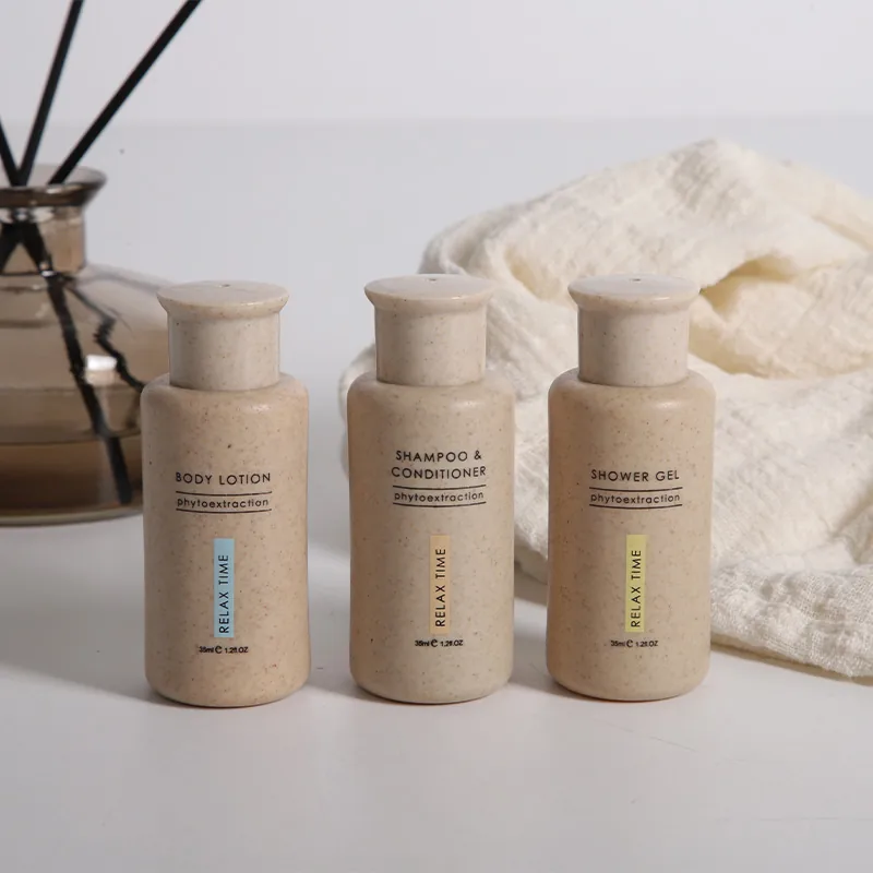 Tres frascos: loción corporal, shampoo y acondicionador, y gel de ducha, junto a una toalla blanca.